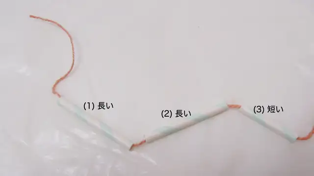 ストローを麻ひもに通して結んでいく